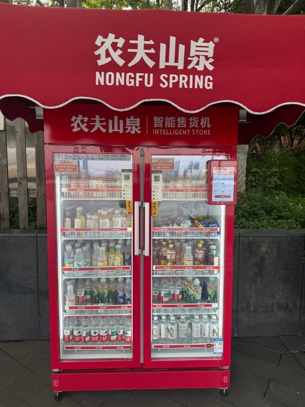 A red Nongfu Spring 'intelligent store' — an unmanned fridge stocked with drinks.